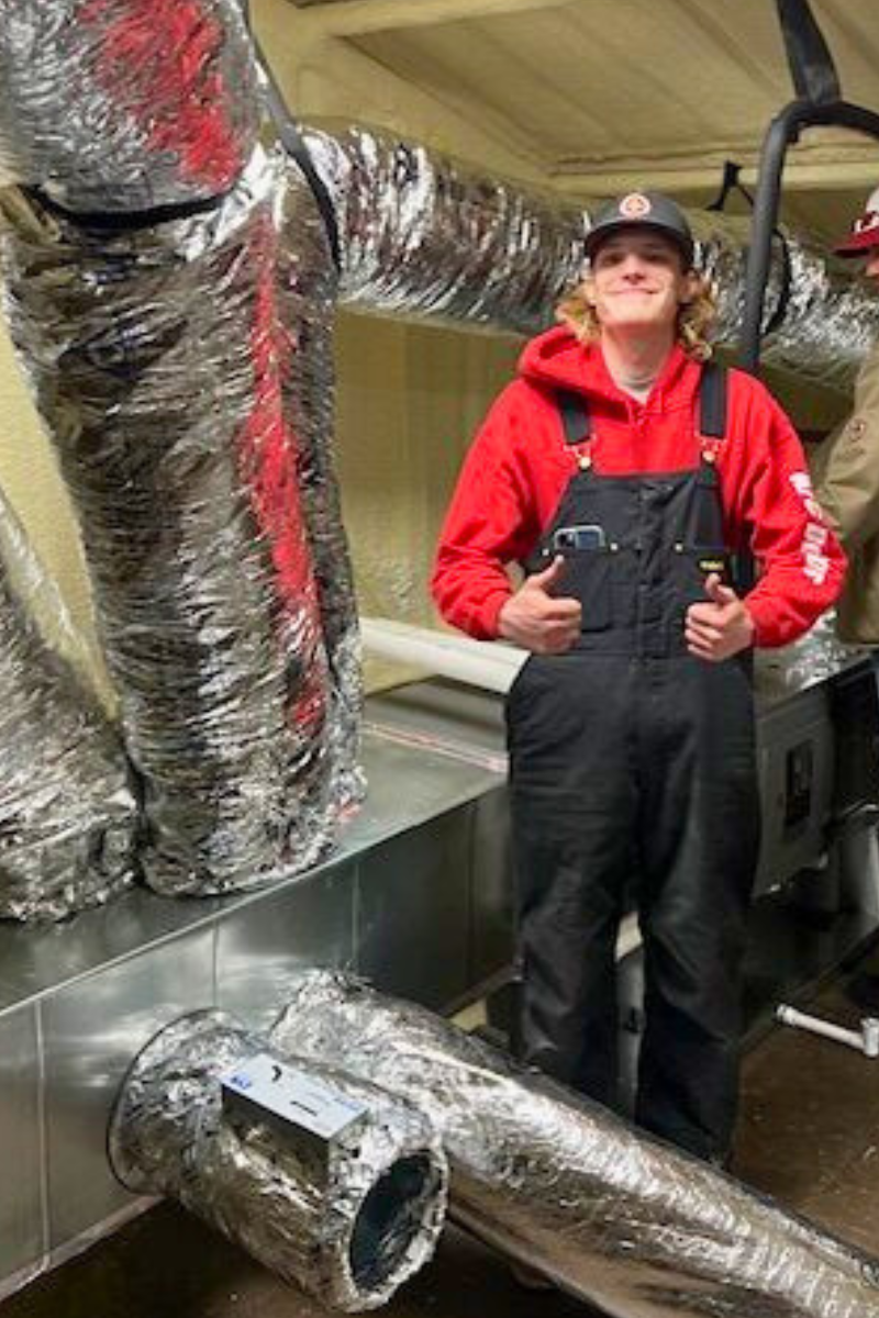 Bryson Wilson standing next to another man and ac duct work.