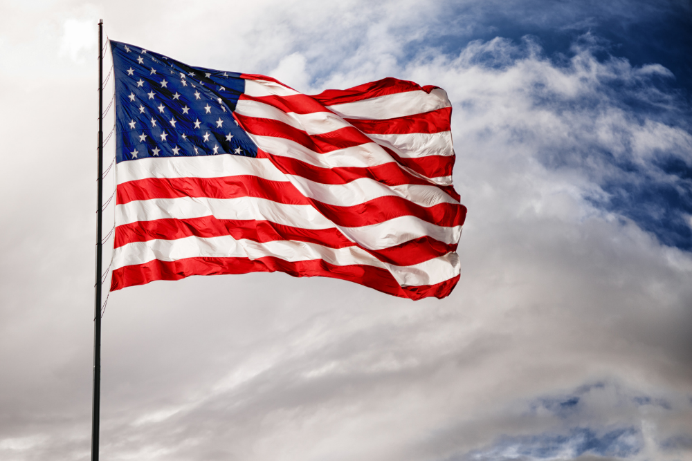 American Flag waving in the sky with clouds in the background.